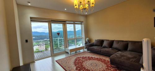 a living room with a couch and a large window at Yangpyeong Sunset Pool Villa Pension in Yangpyeong