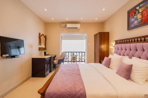 a bedroom with a large bed and a flat screen tv at Emperor Ozran by Alaya Stays in Vagator