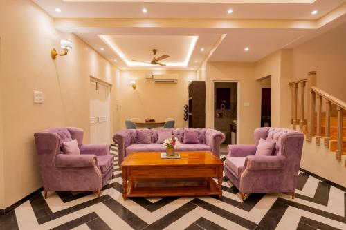 a living room with purple chairs and a table at Emperor Ozran by Alaya Stays in Vagator