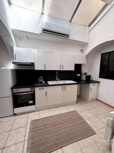 une cuisine avec des armoires blanches et un évier dans l'établissement Appartement maison mas provençal, à Pélissanne