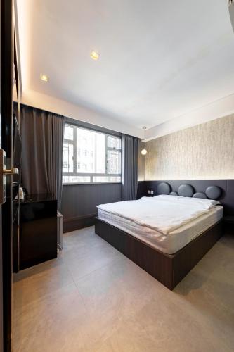 une chambre avec un grand lit et une grande fenêtre dans l'établissement 薈棧賓館 Blooms-bury inn, à Hong Kong