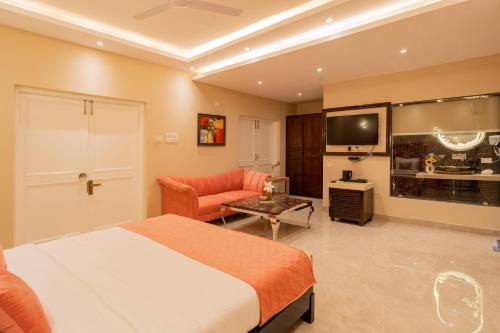a bedroom with a bed and a couch and a tv at Emperor Ozran by Alaya Stays in Vagator