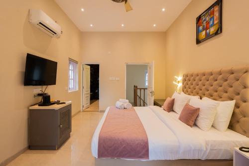 a bedroom with a large bed and a flat screen tv at Emperor Ozran by Alaya Stays in Vagator