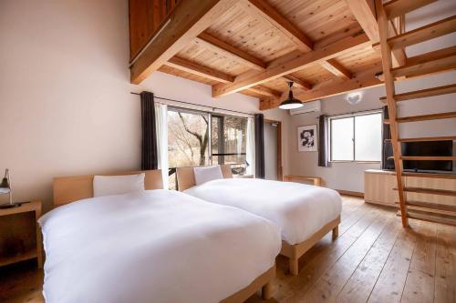 a bedroom with two beds and a large window at Hanare no Yado Hanagokoro in Minamioguni