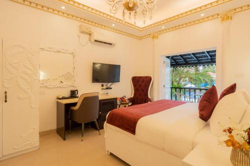 a bedroom with a bed and a desk and a television at Emperor Ozran by Alaya Stays in Vagator