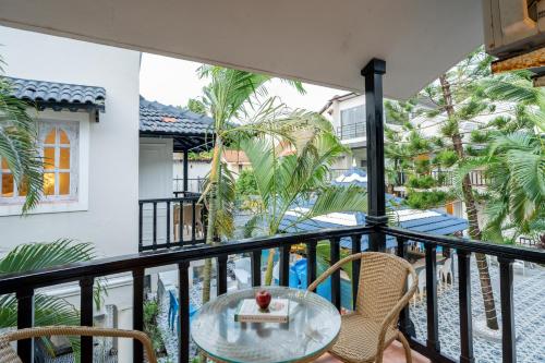 a balcony with a table and chairs and palm trees at Emperor Ozran by Alaya Stays in Vagator