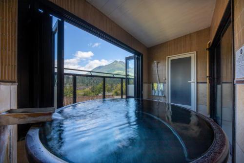 a large bath tub in a room with a large window at Yufudake Ichibo no Yado Kirara in Yufuin