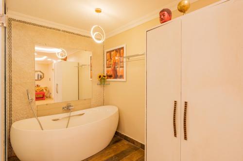 a white bathroom with a tub and a sink at Emperor Ozran by Alaya Stays in Vagator