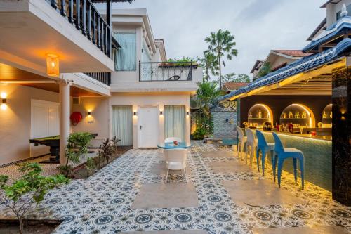 an outdoor patio with chairs and a pool at Emperor Ozran by Alaya Stays in Vagator