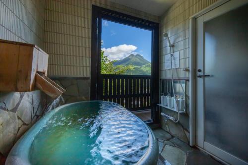 a bathroom with a tub with a view of a mountain at Yufudake Ichibo no Yado Kirara in Yufuin