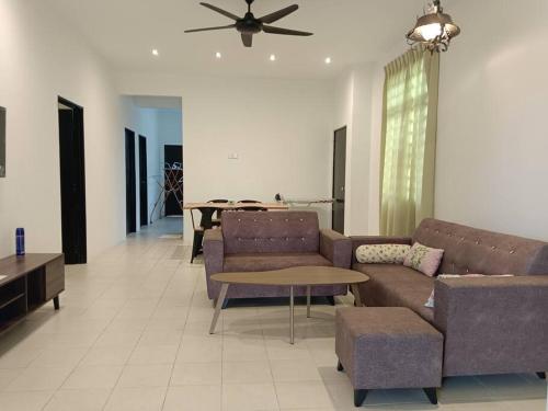 a living room with couches and a ceiling fan at Cozy, Spacious Gambang Homestay in Gambang