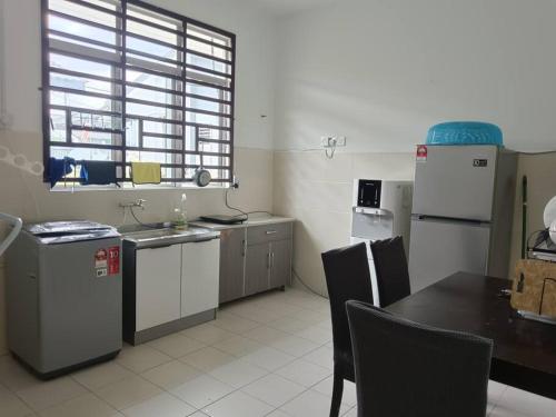 a kitchen with white appliances and a table and a window at Cozy, Spacious Gambang Homestay in Gambang