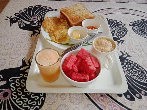 a plate of food with fruit and toast and a drink at Dumas Guest House in Puducherry