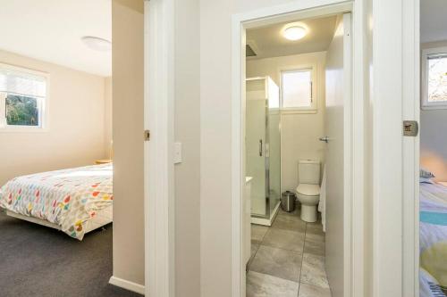a bedroom with a bed and a bathroom with a toilet at Family friendly - 10min drive to Chch city centre in Christchurch