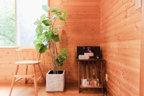 a room with a wooden wall with a desk and a plant at 4月リニューアルOpen! 全室エアコン完備! Deerview Lodge 山中湖 in Yamanakako