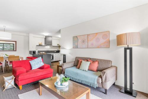 a living room with a couch and a red chair at Apartment with City Views in East Perth in Perth