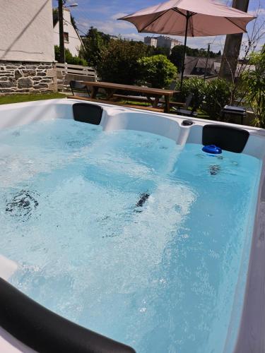 - un bain à remous avec de l'eau bleue et un parasol dans l'établissement Authentique maison Morlaisienne, à Morlaix