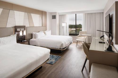 a hotel room with two beds and a desk at Palm Beach Gardens Marriott in Palm Beach Gardens