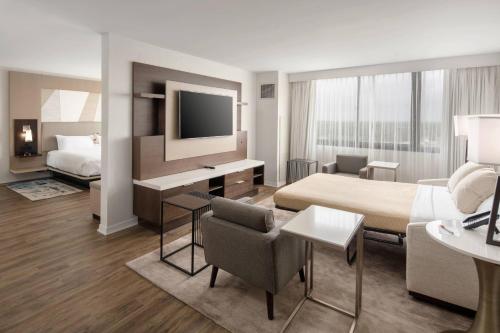 a hotel room with a bed and a desk with a television at Palm Beach Gardens Marriott in Palm Beach Gardens