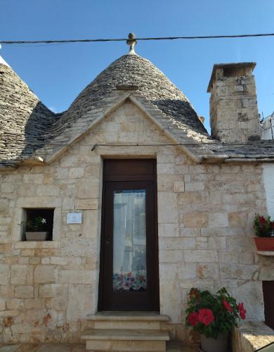 a stone building with a door with flowers on it at IL TRULLO GENTILE ALBEROBELLO in Alberobello