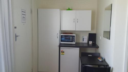 a small kitchen with a microwave and a refrigerator at Kadina Village Motel in Kadina
