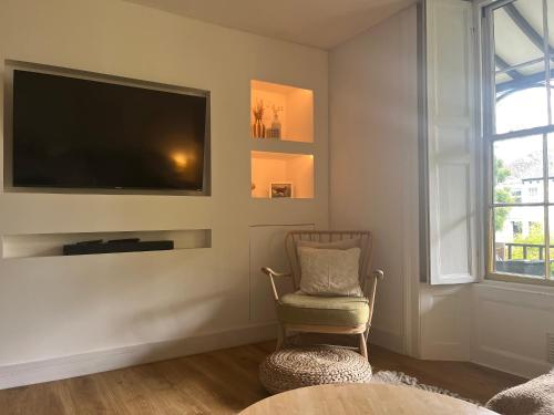 a living room with a chair and a flat screen tv at Cosy, convenient flat in Falmouth in Falmouth
