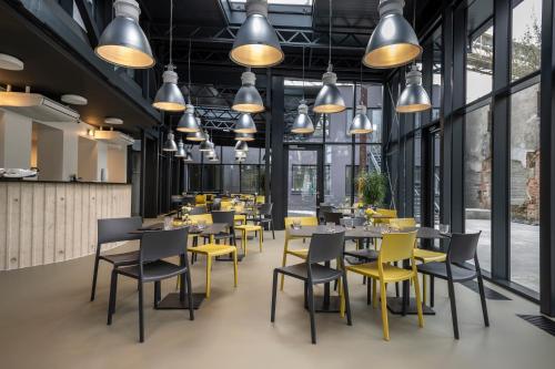 a restaurant with tables and yellow chairs and lights at Design Hotel VP1 ART in Ostrava