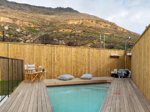 a swimming pool with a wooden fence and a mountain at Arc Guest House in Cape Town