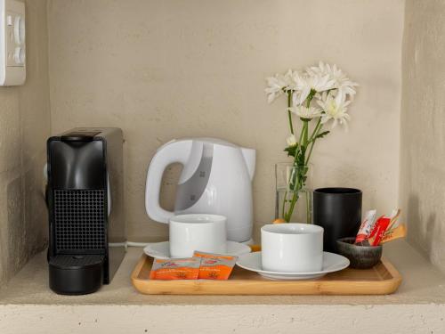a counter with a coffee maker and cups and flowers at Arc Guest House in Cape Town
