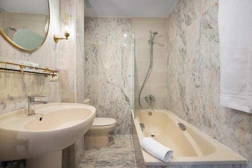 a bathroom with a sink and a toilet and a tub at Crisol Mesón del Cid in Burgos