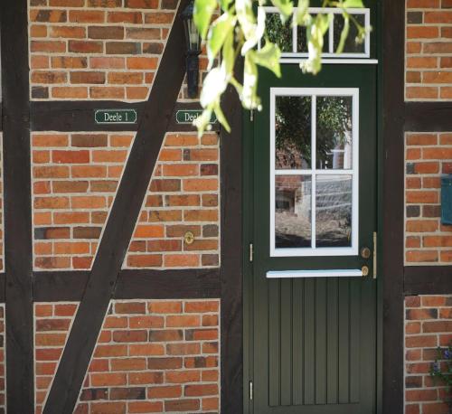 a green door on a brick building with a window at Beekenhof in Bommelsen