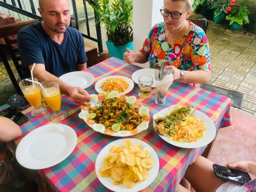 a group of people sitting at a table with plates of food at Deshan Homestay & Restaurant in Tangalle