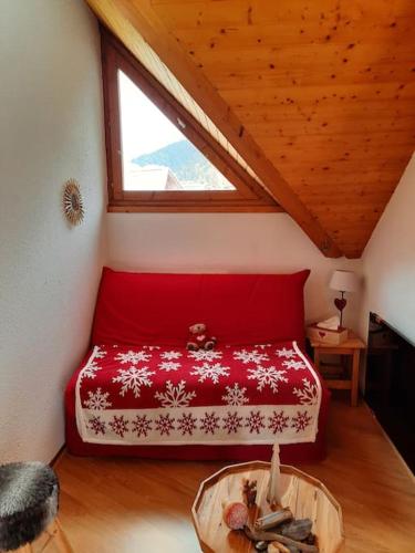 - une chambre mansardée avec un lit rouge dans l'établissement Appartement au pied des pistes, aux Contamines-Montjoie