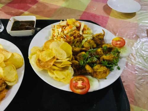 a plate of food with potato chips and tomatoes on a table at Deshan Homestay & Restaurant in Tangalle