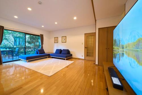 a living room with a large screen tv and blue couches at Suite Villa Izukogen Prime in Ito