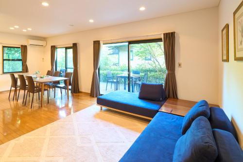 a living room with a blue couch and a dining room at Suite Villa Izukogen Prime in Ito