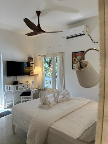a bedroom with a white bed with a ceiling fan at Oceanic - Luxury Boutique Hotel in Palolem