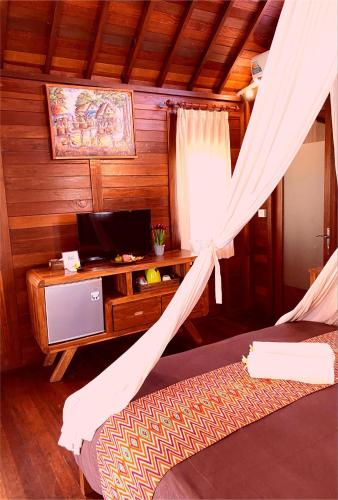 a bedroom with a desk and a bed with a curtain at D'padang villa & Homestay in Uluwatu