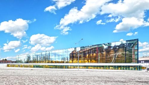 a large glass building with a blue sky and clouds at Design Hotel VP1 ART in Ostrava