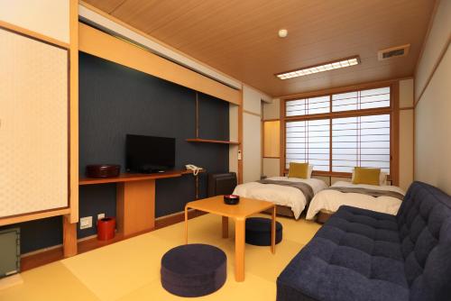 a room with two beds and a couch at Dogo-no-Yado Katsuragi in Matsuyama