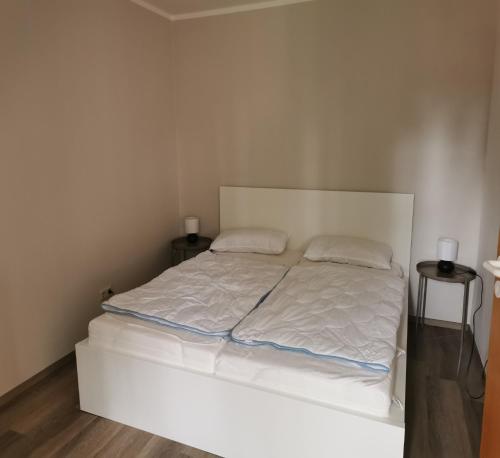 a bedroom with a white bed with two pillows at Beekenhof in Bommelsen