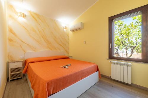 sypialnia z łóżkiem z pomarańczowymi prześcieradłami i oknem w obiekcie Villetta Residence Porto Corallo w mieście Villaputzu