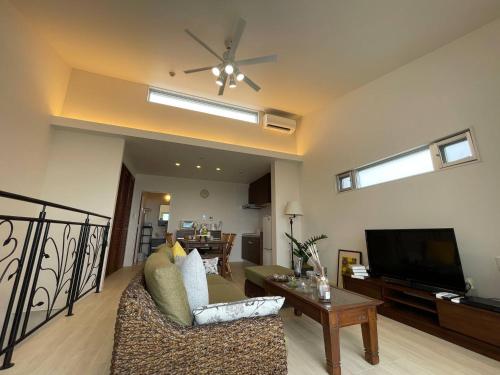 a living room with a couch and a flat screen tv at Alpha Terrace Onna Hills in Onna