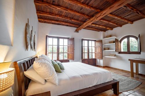 a bedroom with a large bed in a room with windows at Can Pla Roig con vistas al Mar y la Puesta de Sol in Sant Joan de Labritja