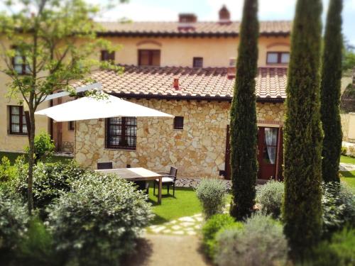 Una mesa y una sombrilla en un jardín con un edificio. en vicino a San Gimignano, relax tra piscina e natura, fast internet STARLINK, en Gambassi Terme