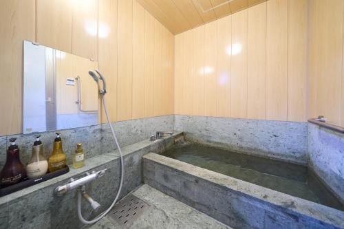 a bathroom with a tub with a shower at Suite Villa Hakone Gora in Hakone