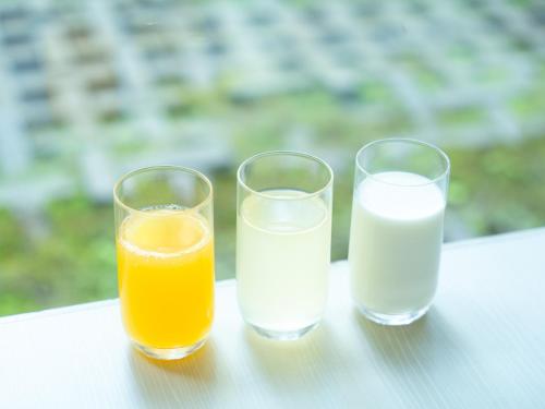 two glasses of orange juice and a glass of milk at APA Hotel Karuizawa Ekimae Karuizawaso in Karuizawa
