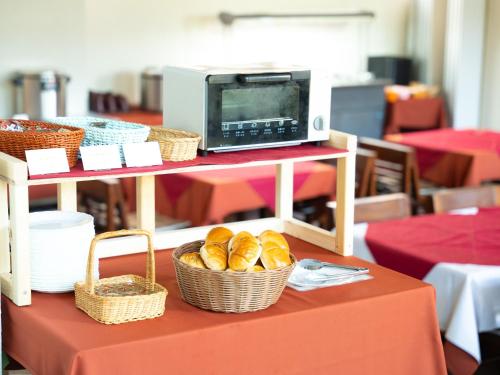a table with baskets of bread and a microwave at APA Hotel Karuizawa Ekimae Karuizawaso in Karuizawa