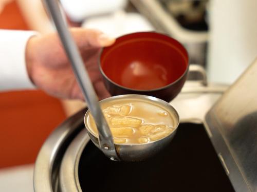 a person holding a cup of coffee on a stove at APA Hotel Karuizawa Ekimae Karuizawaso in Karuizawa