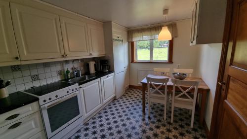a kitchen with white cabinets and a table in it at Saltögården in Strömstad